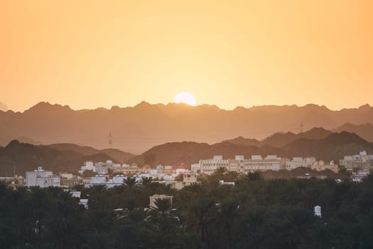 City against mountain range at idyllic sunset. Nizwa in Sultanate of Oman.