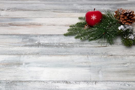Christmas or Happy New Year decoration background. Composition from sparkling christmas tree branches with a red apple and fir cones on a rustic wooden background. Top view copy space.