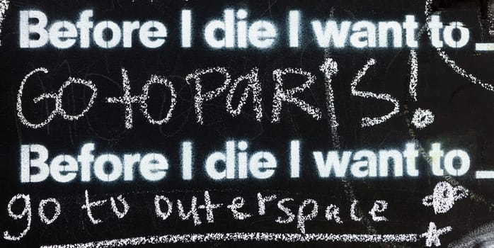 Fragment of a blackboard reading: Before I die I want to go to Paris