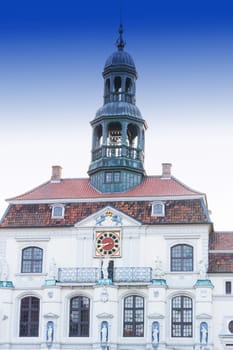Lueneburg, Lower Saxony, Germany - July 27, 2018:.Vintage street lamp lantern with flowerbed. Historic city hall in the background in Lueneburg Germany.