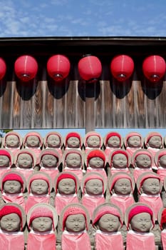 Row of buddhist mizuko jizo statues with red bib, hat