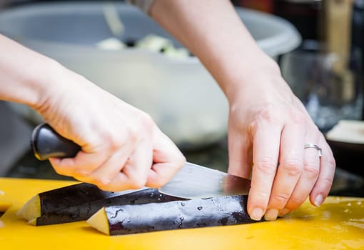 Closeup of womans hands cutting eggplant