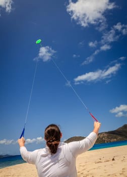 A woman is flying a kite on a tropical beach in the Caribbean
