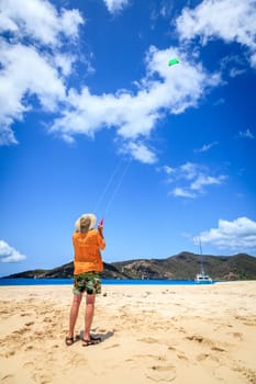 A man is flying a kite on a tropical beach in the Caribbean