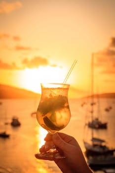 A glaass with mojito cocktail against sunset skies in British Virgin Islands