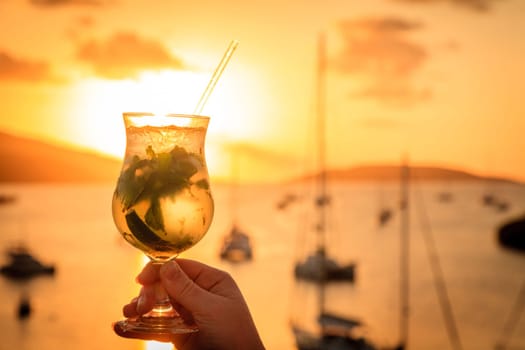 A glaass with mojito cocktail against sunset skies in British Virgin Islands