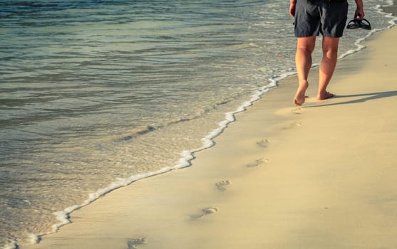 A person walkng along a sand beach on an island in BVI