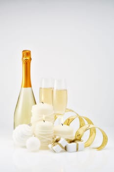 Christmas and New Year still life with two wineglasses of champagne, bottle, gift boxes and Christmas ornaments isolated on a white background. Christmas and New Year greeting card