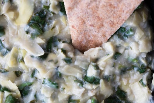 Close up of vegan spinach artichoke dip and whole wheat pita bread