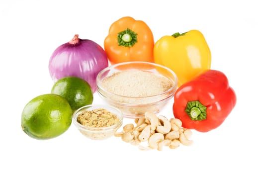 Nutritional yeast surrounded by other fresh ingredients for creamy vegan peppers and onions.