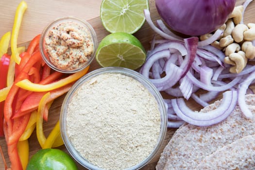Nutritional yeast surrounded by other fresh ingredients for creamy vegan peppers and onions.