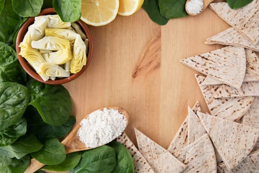 Artichoke hearts, spinach, lemon and other ingredients for vegan dip flat lay with copy space