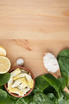 Artichoke hearts, spinach, lemon and other ingredients for vegan dip flat lay with copy space