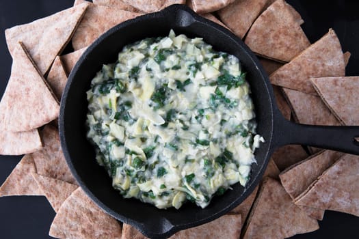 Pan with fresh vegan spinach artichoke dip and whole wheat pita bread.