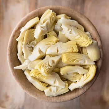 Quartered artichoke hearts in wooden bowl viewed from above