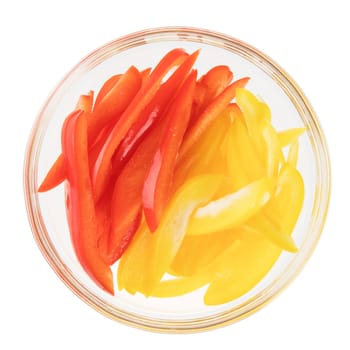 Sliced red and yellow peppers in a glass bowl, isolated on white and viewed from above.