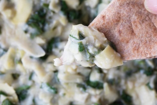 Close up of vegan spinach artichoke dip and whole wheat pita bread