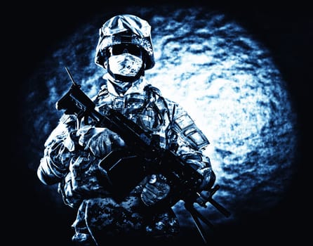 United States Marine Corps soldier in camouflage protective ammunition with hiding identity, armed with machine gun blue tone studio shot. Army infantry posing with weapon, spotlight in background