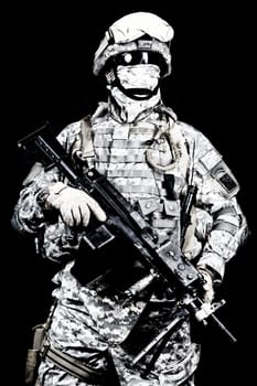 Marine with hiding identity, protected with helmet and body armour in digital camouflage combat uniform posing with light machine gun equipped infrared laser aiming light isolated on black background