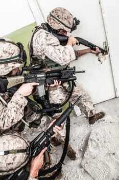Marine assault team, counter-terrorism squad members, commando fighters in body armor, armed with service rifles, stalking through corridor to closed door, clearing rooms in abandoned city building
