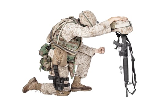 Army soldier in sorrow for fallen comrade, standing on knee, leaning on rifle with helmet and two dog tags on chain, studio shoot isolated on white. Military funeral honors, grief for killed in action