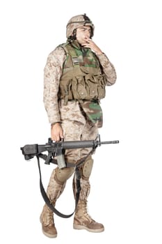 Studio shoot of army, marine machine gunner in camouflage combat uniform and body armor, standing with machine gun, isolated on white