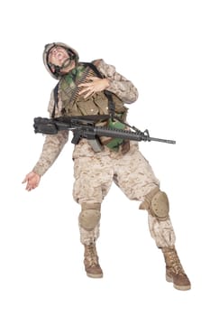 Studio shoot of army soldier in combat uniform and body armor, screaming, clutching chest, dropping weapons and falling down after being fatally shot in military firefight. Marine gets shot in battle