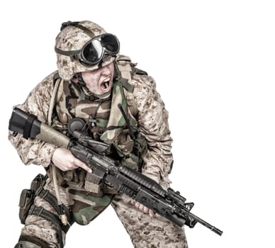 Studio shoot of modern infantry soldier, U.S. marine rifleman in combat uniform, helmet and body armor, screaming and crouching down with assault service rifle in hands isolated on white background