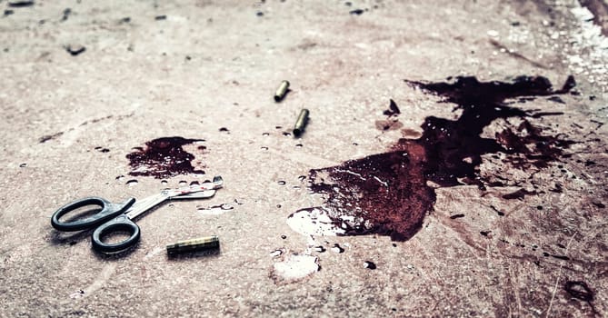 Trauma shears or bandage scissors lying on floor with stains of human blood around. Blood loss and bleeding stop, emergency medical aid for gunshot wounds, tactical combat casualty care on battlefield