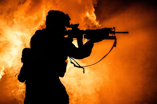 Silhouette of modern infantry soldier, elite army fighter in tactical ammunition and helmet, standing with assault service rifle in hands