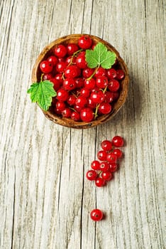 Fresh red currant berries with leaf on wooden background close up