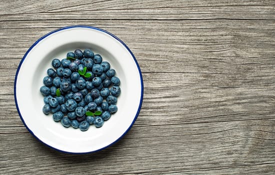 Fresh Blueberries in a bowl on wooden background