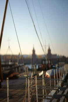 The railing of an anchored ship on the banks of the Spree with blurred silhouettes of the Oberbaum bridge in the background..