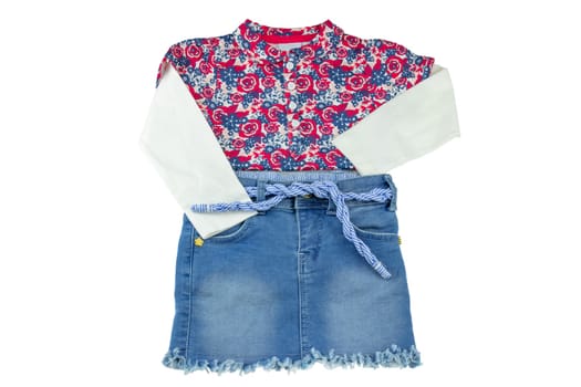 Girls clothes. Fashionable little girl shirt with floral print and a blue jeans skirt for children.  Concept summer fashion for childs.