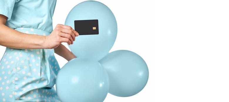 Caucasian female hand holding black premium credit bank card and blue festive air balloons on white background. digital business finance