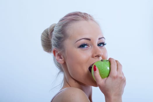 nice smile of a beautiful girl biting a green apple