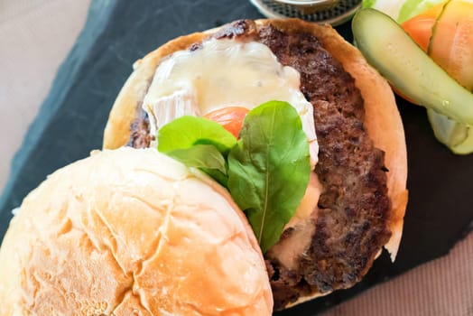 Homemade overload beef hamburger with fresh vegetables and cheese with fries