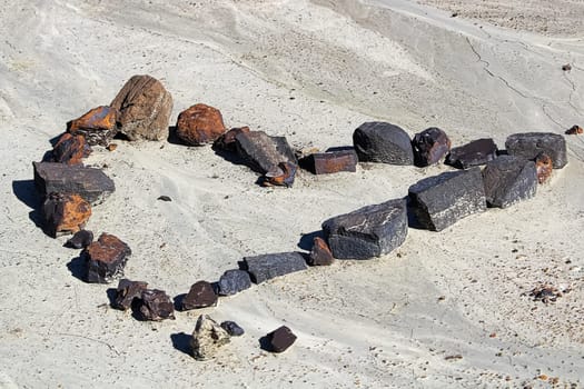 A set of rocks in the shape of a heart in the dried mud.