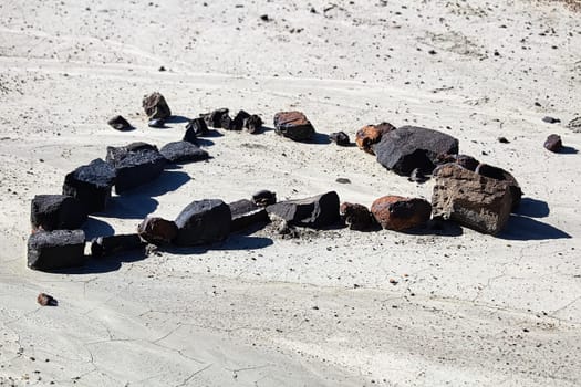 A set of rocks in the shape of a heart in the dried mud.
