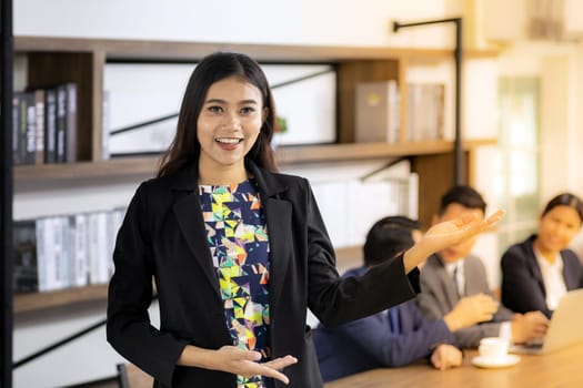 Portrait of asian confidence Businesswoman stand in front of table in meeting room in cafe with business team in background using for coporate background work