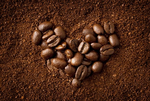 Heart shaped coffee beans on coffee powder background