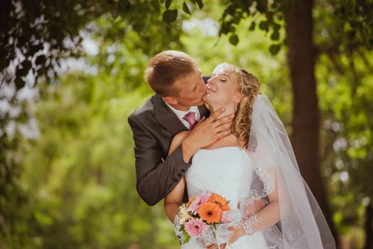 Bride and groom in a park kissing.couple newlyweds bride and groom at a wedding in nature green forest are kissing photo portrait.Wedding Couple Love