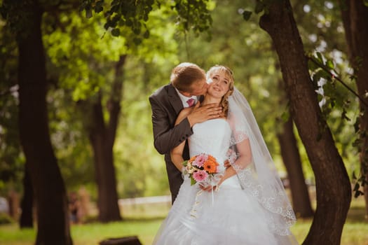Bride and groom in a park kissing.couple newlyweds bride and groom at a wedding in nature green forest are kissing photo portrait.Wedding Couple Love