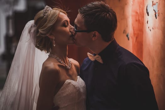 Closeup portrait of bride and groom kissing in ancient tunnel made of bricks