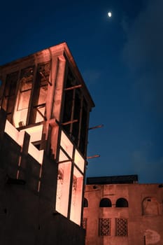 Moon over traditional buildings of Al Bastakiya district of old Dubai