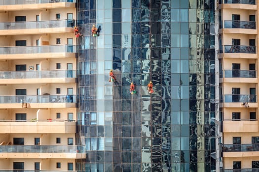 Maintenance crew is cleaning windows of a skyscraper in Dubai, UAE