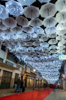 AGUEDA, PORTUGAL - CIRCA DECEMBER 2018: The beauty of white umbrellas iluminated by Christmas lights decorating the streets of Agueda Portugal