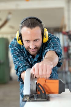 young worker with hand saw in a carpenter's workshop