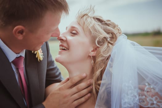Beautiful bride and groom standing in grass and kissing. Wedding couple fashion shoot.