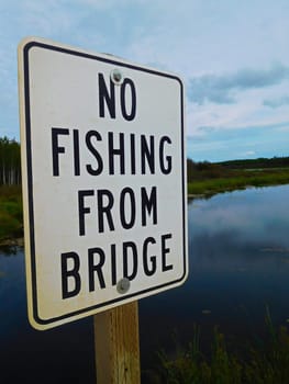 No Fishing From Bridge Sign Infront of a Beautiful River.